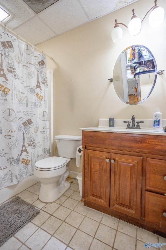 full bathroom with a drop ceiling, shower / bath combo, tile patterned floors, toilet, and vanity