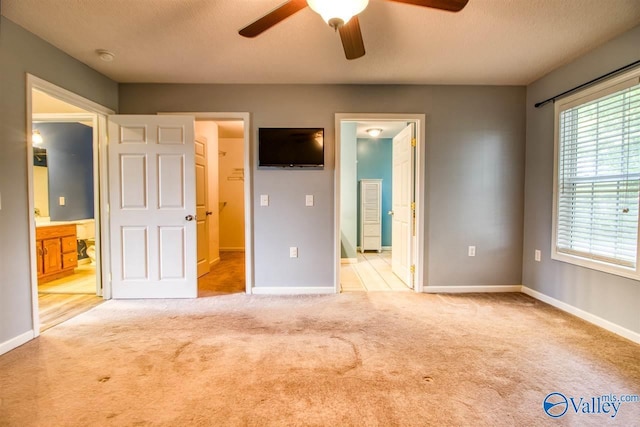unfurnished bedroom featuring baseboards, ensuite bathroom, a textured ceiling, and carpet flooring