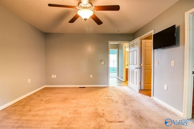 unfurnished room featuring light carpet, baseboards, a textured ceiling, and a ceiling fan