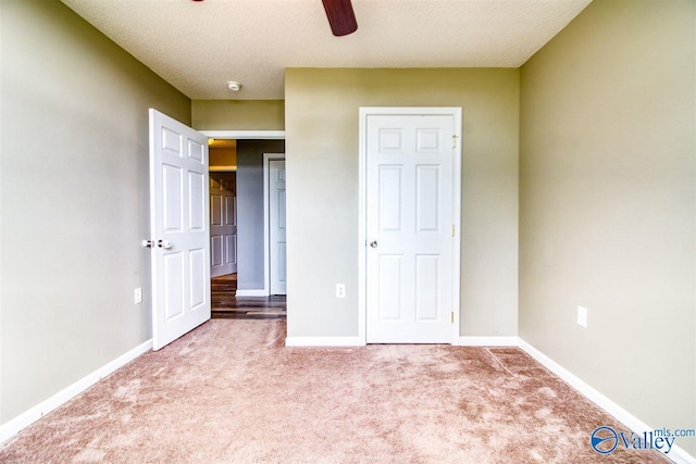 unfurnished bedroom featuring a textured ceiling, baseboards, carpet, and a ceiling fan