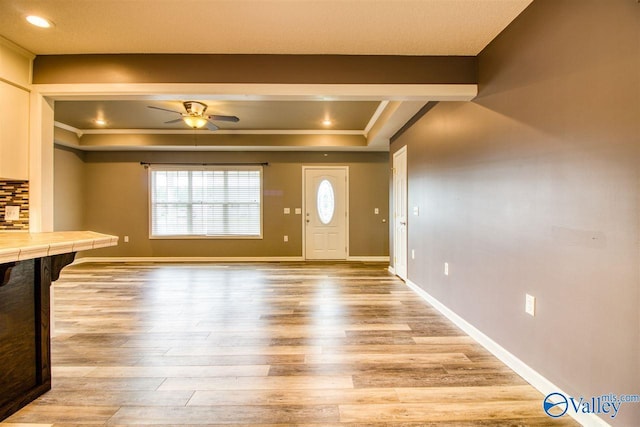 unfurnished living room featuring light wood-style flooring, plenty of natural light, a ceiling fan, and baseboards
