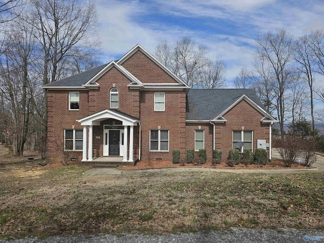 colonial inspired home with a shingled roof and brick siding