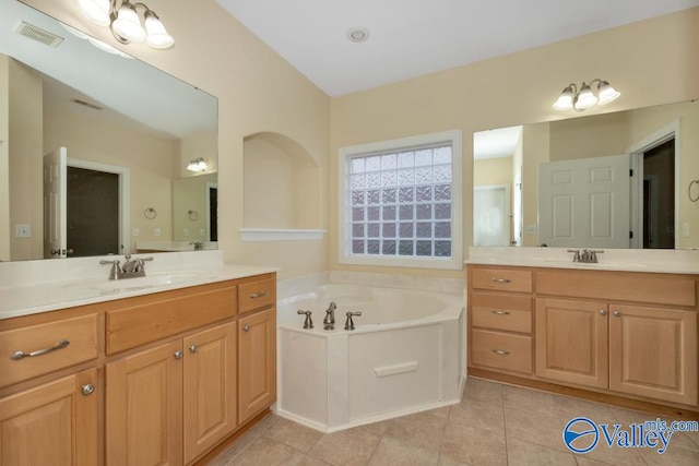 bathroom with tile patterned floors, a tub, and vanity