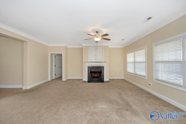 unfurnished living room with ceiling fan, a tile fireplace, ornamental molding, and light colored carpet