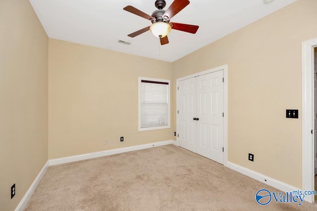 unfurnished bedroom with light colored carpet, a closet, and ceiling fan