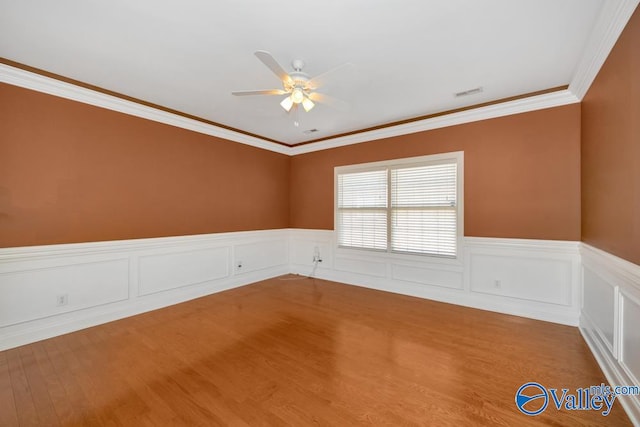 empty room featuring hardwood / wood-style floors, crown molding, and ceiling fan