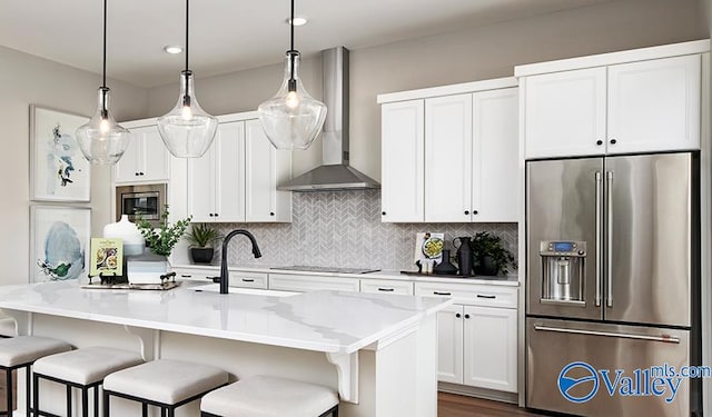 kitchen with stainless steel appliances, wall chimney range hood, backsplash, white cabinetry, and a breakfast bar area