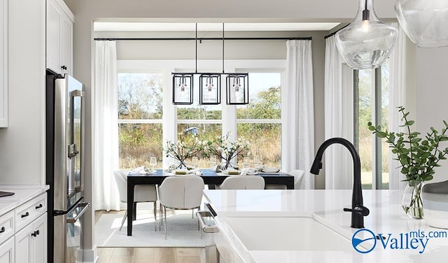 kitchen featuring freestanding refrigerator, light countertops, a sink, and plenty of natural light