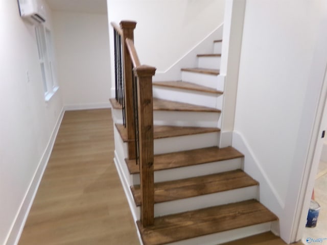 stairway with a wall unit AC and hardwood / wood-style flooring