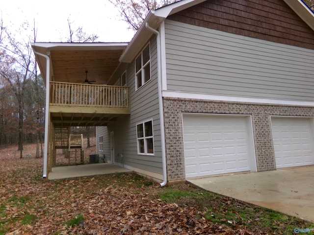 view of side of property featuring a balcony, a garage, and central AC unit