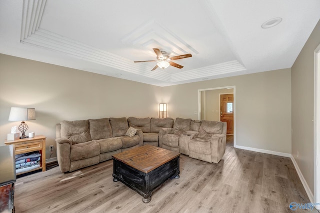 living room featuring a raised ceiling, light hardwood / wood-style floors, and ceiling fan