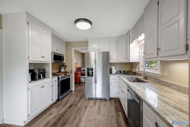 kitchen with white cabinets, appliances with stainless steel finishes, and light wood-type flooring