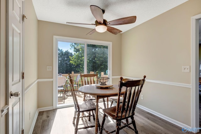 dining room with ceiling fan, a textured ceiling, and dark wood-type flooring