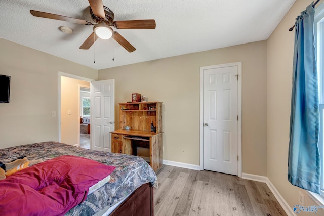 bedroom with light hardwood / wood-style flooring, ceiling fan, and a textured ceiling