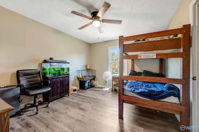 bedroom with ceiling fan, a textured ceiling, and light hardwood / wood-style floors