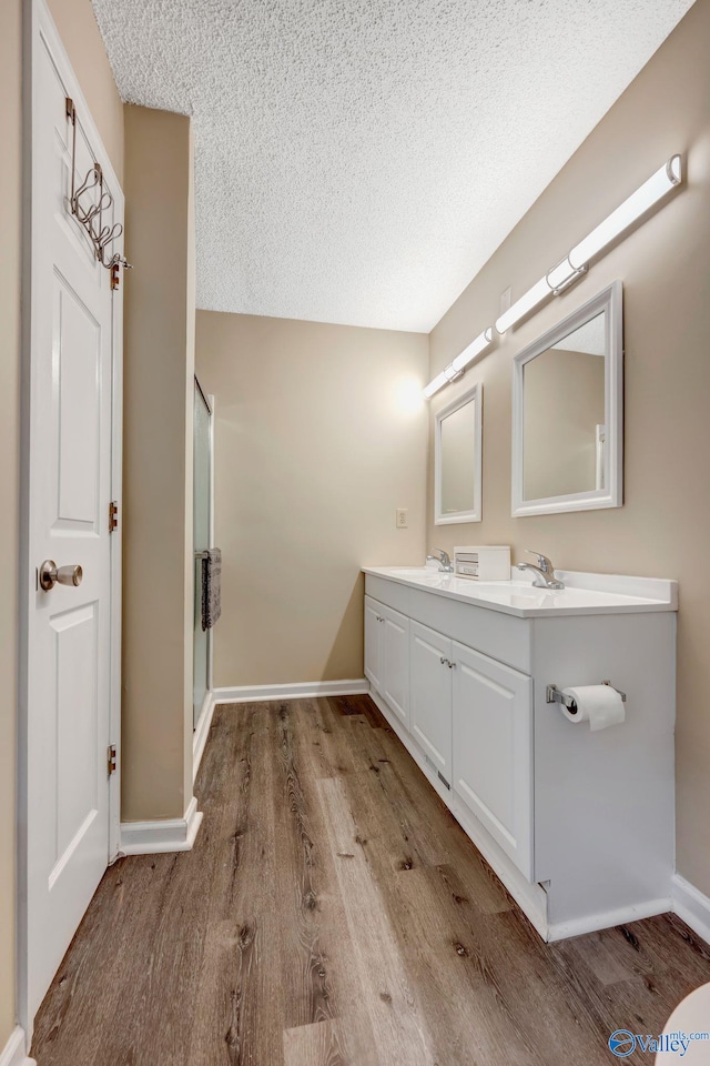 bathroom featuring hardwood / wood-style floors, a textured ceiling, walk in shower, and vanity