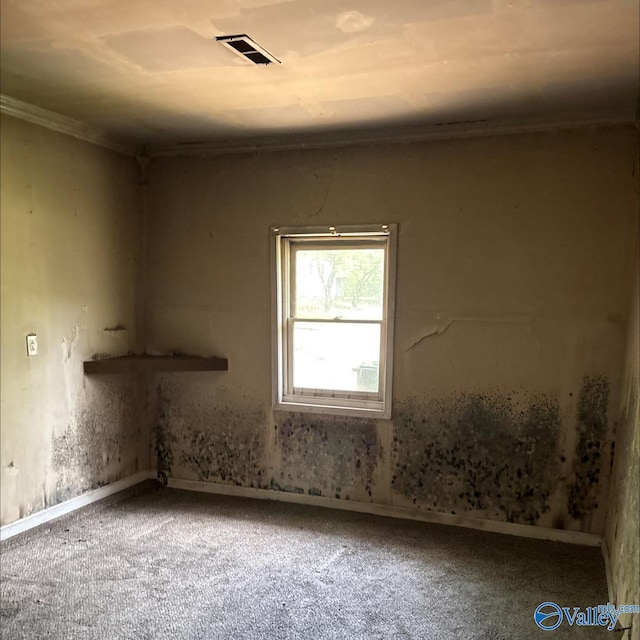 carpeted empty room featuring baseboards, ornamental molding, and visible vents