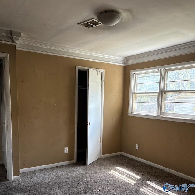 unfurnished bedroom featuring carpet flooring, baseboards, visible vents, and ornamental molding