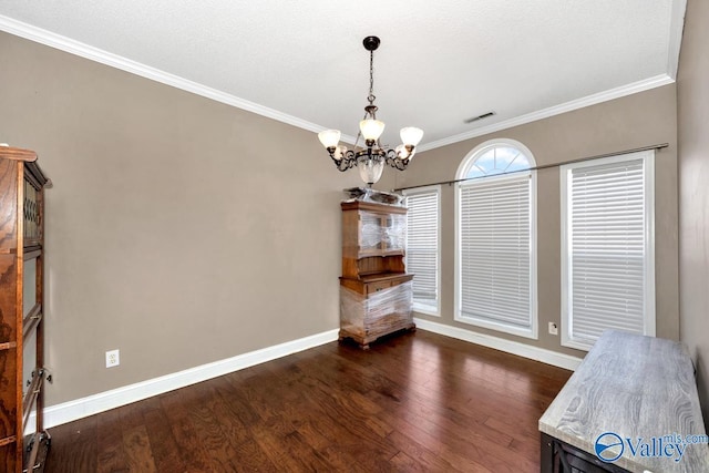 unfurnished dining area featuring dark wood-style flooring, crown molding, visible vents, an inviting chandelier, and baseboards