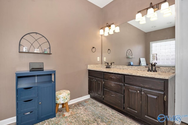 bathroom featuring double vanity, baseboards, and a sink