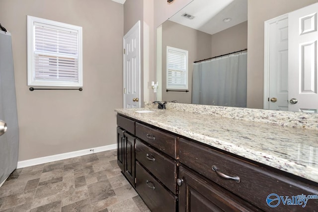 bathroom with stone finish floor, visible vents, vanity, and baseboards