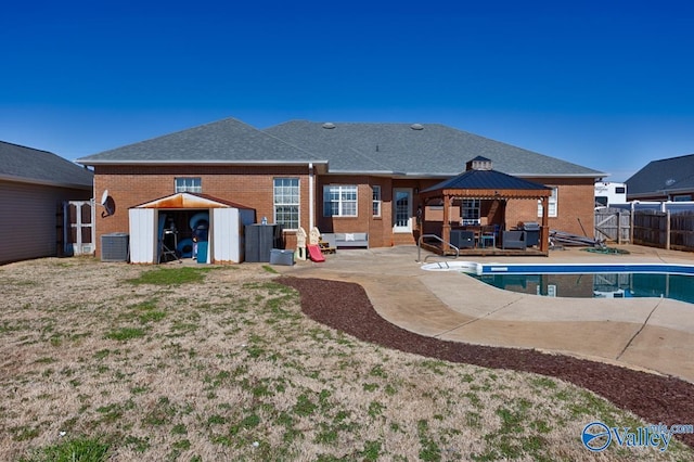 back of house with brick siding, a storage unit, a gazebo, fence, and cooling unit