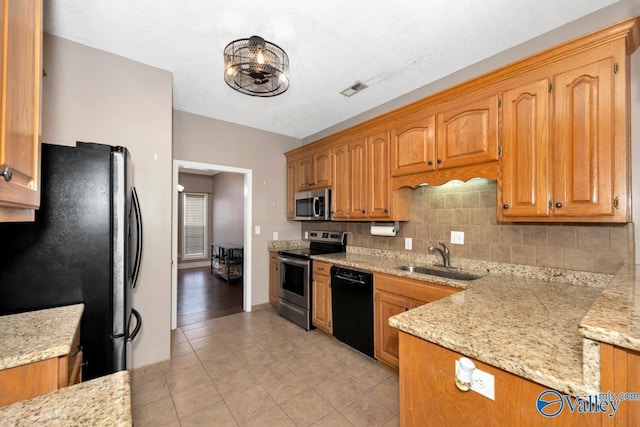 kitchen with light tile patterned floors, a sink, backsplash, brown cabinets, and black appliances