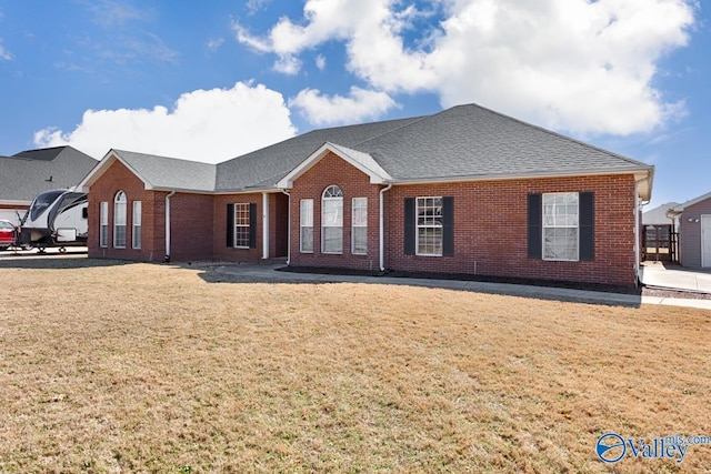 ranch-style home featuring roof with shingles, brick siding, and a front lawn