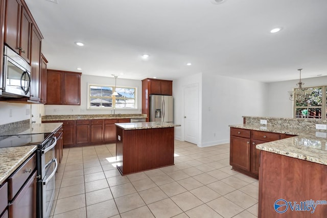 kitchen with appliances with stainless steel finishes, light tile patterned floors, decorative light fixtures, an inviting chandelier, and a kitchen island