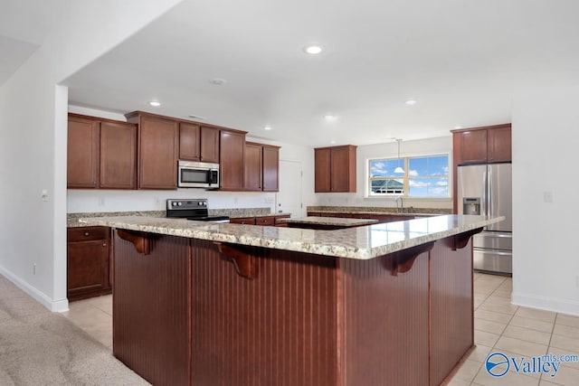 kitchen featuring a kitchen breakfast bar, stainless steel appliances, light stone counters, and a large island