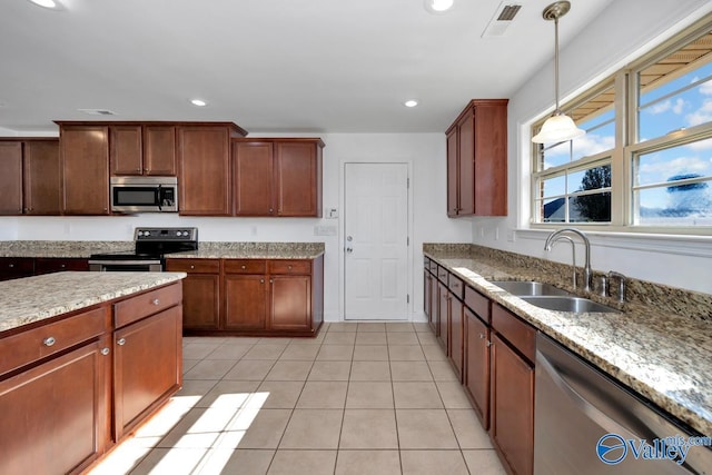 kitchen featuring sink, hanging light fixtures, light stone counters, light tile patterned floors, and appliances with stainless steel finishes