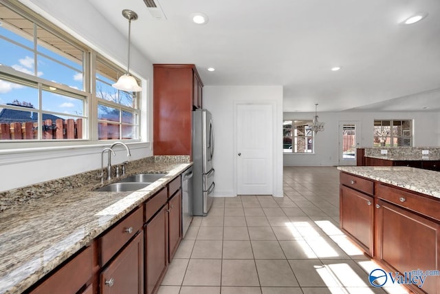 kitchen with light stone counters, hanging light fixtures, a notable chandelier, and sink