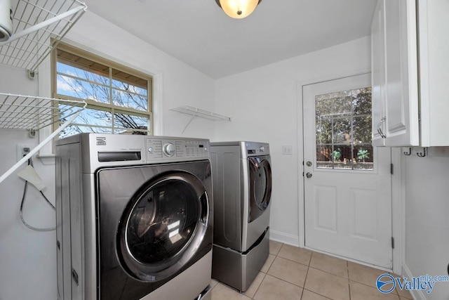 washroom featuring cabinets, independent washer and dryer, light tile patterned floors, and a wealth of natural light