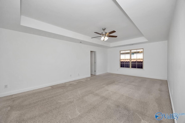 carpeted empty room with a tray ceiling and ceiling fan