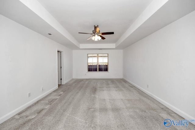 carpeted spare room featuring a raised ceiling and ceiling fan