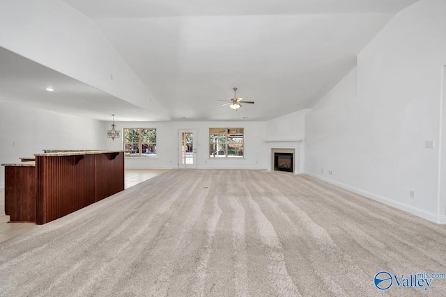 unfurnished living room featuring ceiling fan with notable chandelier, light colored carpet, and lofted ceiling