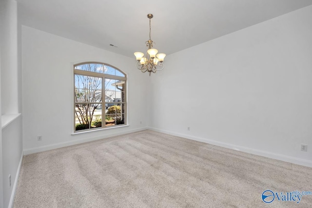 carpeted spare room with a chandelier