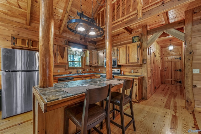 kitchen with beamed ceiling, appliances with stainless steel finishes, light hardwood / wood-style floors, and wood walls