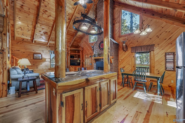 kitchen featuring light hardwood / wood-style floors, wood walls, beamed ceiling, and hanging light fixtures