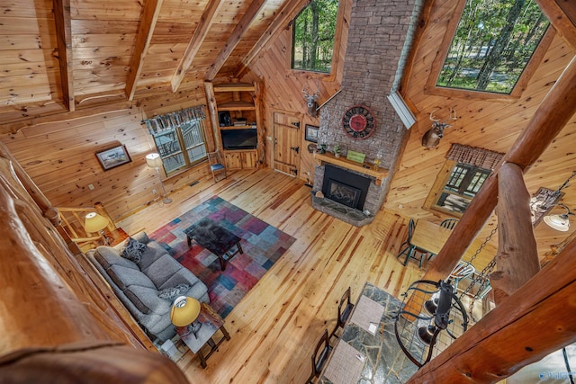 living room with wood ceiling, beamed ceiling, hardwood / wood-style floors, a fireplace, and wood walls