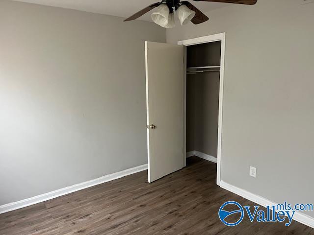 unfurnished bedroom with ceiling fan, dark wood-type flooring, and a closet
