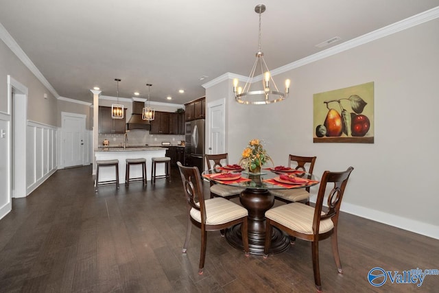 dining area featuring dark wood-type flooring, crown molding, sink, and a chandelier