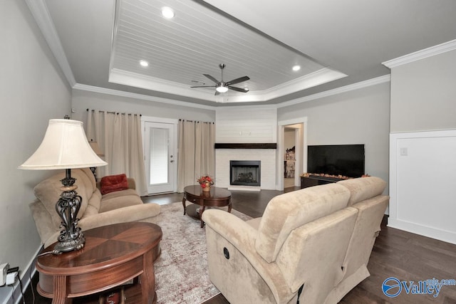 living room with dark wood-type flooring, ceiling fan, crown molding, and a raised ceiling