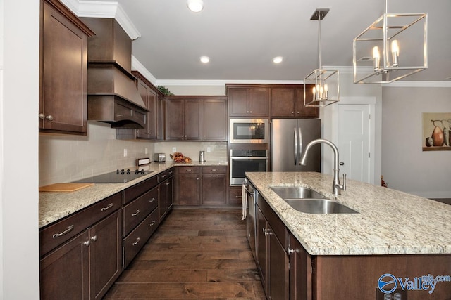 kitchen featuring dark hardwood / wood-style floors, hanging light fixtures, stainless steel appliances, a center island with sink, and sink