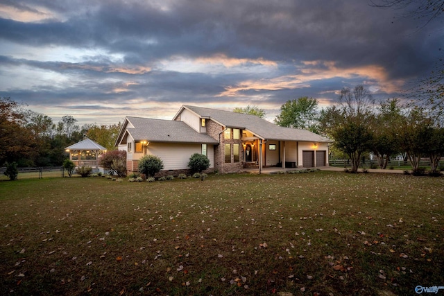 back house at dusk featuring a lawn