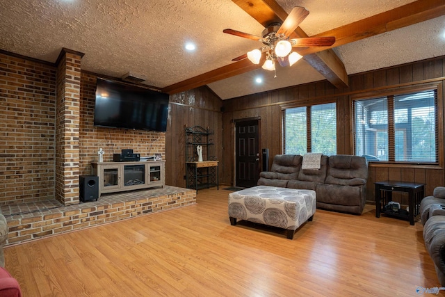 living room with light hardwood / wood-style floors, wooden walls, a textured ceiling, and ceiling fan