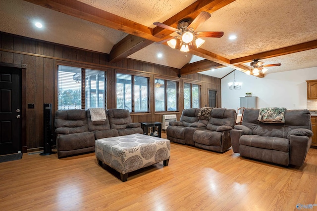 living room with wood walls, ceiling fan, a textured ceiling, vaulted ceiling with beams, and light wood-type flooring