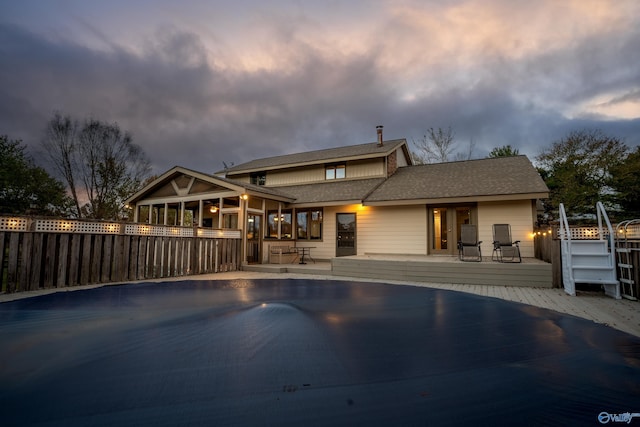 back house at dusk featuring a patio and a pool side deck