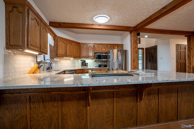 kitchen featuring stainless steel appliances, a textured ceiling, kitchen peninsula, and tasteful backsplash