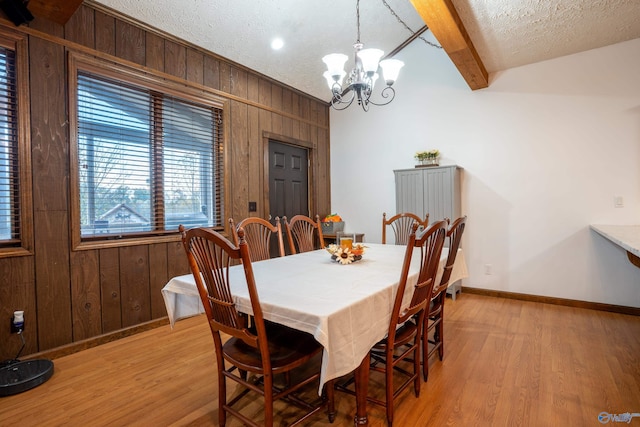 dining area with wood walls, light wood-type flooring, and a textured ceiling